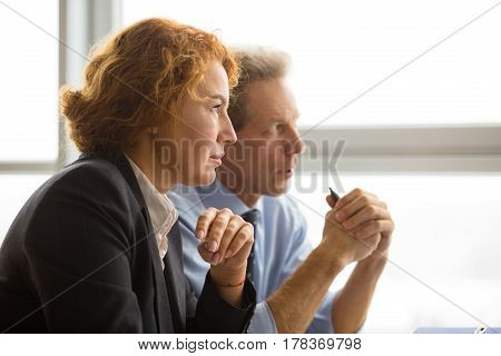 Business team having negotiations with their business partners while sitting in board room in office. People solving serious problems, issues, objectives.