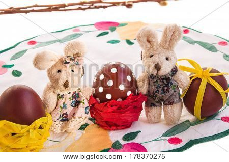 Easter composition with couple of funny toy rabbits dressed like a boy and girl eggs and willow branches in the background. Horizontal closeup.