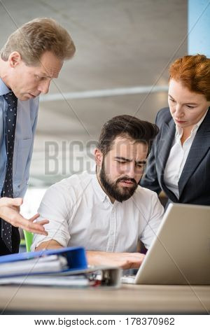 Mobbing, stress, work, scandal concepts. Angry bosses man and woman screaming and shouting at their worker while he is working on laptop computer.
