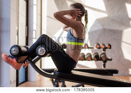 portrait of an athletic woman doing exercising abdominals work-out lying in gym at luxury hotel at summer.