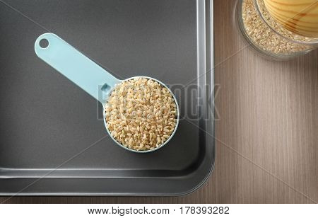 Measure scoop with brown rice on dripping pan