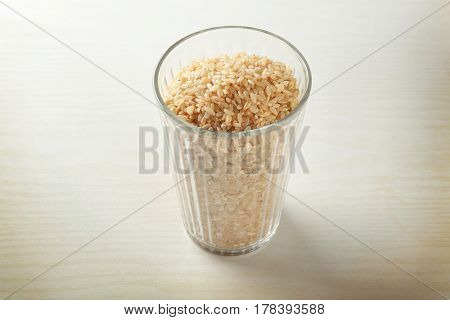 Faceted glass full of brown rice on white table