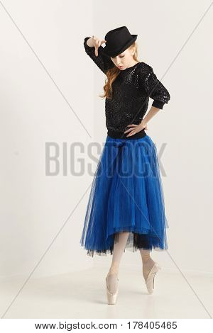 Sweet hipster ballerina in a tutu pointe shoes and glasses dancing with hat. Modern dance. Youth culture