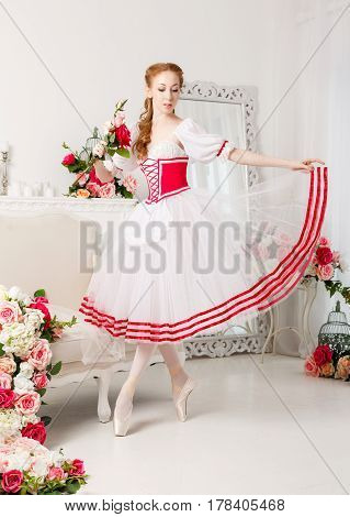Sweet ballerina in a stage costume holds a bouquet of spring flowers. Retro dress. She straightens her skirt.