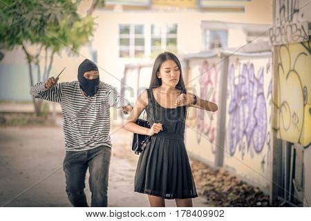 Street thief holding knife and trying to steal and run away the shoulder bag while woman looking watch Vintage tone style