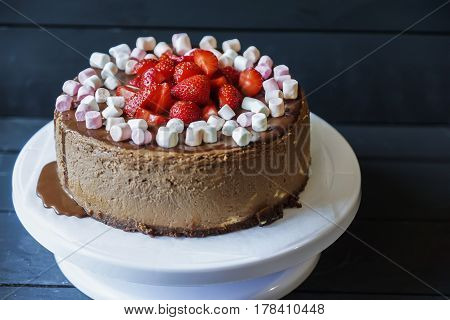Delicious cake with fresh strawberries and dark chocolate sauce and plate with marshmallows
