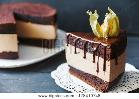 Delicious cake with chocolate sauce, fruit and plate with slace of this cake on lace napkin