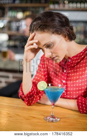 Tired woman with head in hand in a bar