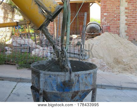 Concrete mix pouring into container for lifting over rooftops
