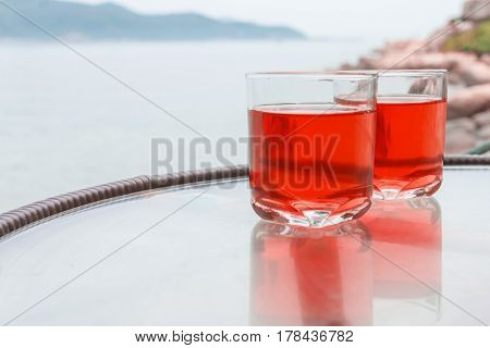 Two glasses of fresh red juice on the table near the sea.