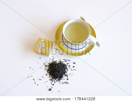 Cup of tea with tea leaves and scattered pile isolated on a white background