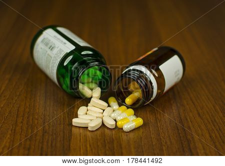View of two glass with pills lying side by side on a wooden background