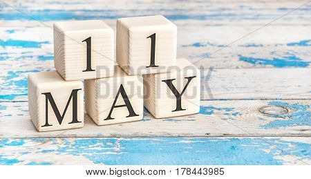May 11th. Wooden cubes with date of 11 May on old blue wooden background.