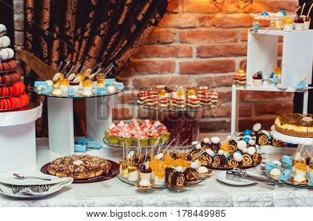 blue white sweets on gilded paper on the wedding candybar. Brick wall on a background.