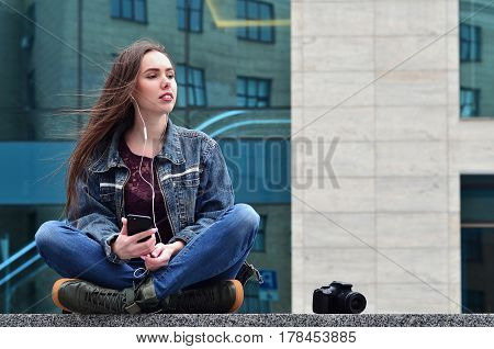A Girl Photographer Uses A Smartphone And Sits On A Granite Parapet