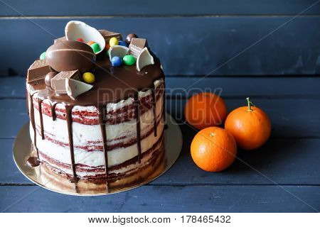 Delicious chocolate cake with dark chocolate sauce and with chocolate candies, tangerines