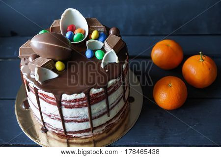 Delicious chocolate cake with dark chocolate sauce and with chocolate candies, tangerines