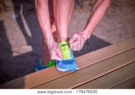Athlete during training tying shoelaces on sneakers summer.
