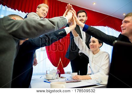 Six businessmen are highfiving each other after closing a deal