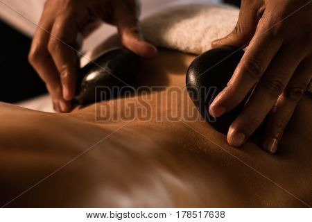 Closeup of massage with hot stones. Spa treatment.