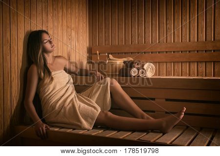 The young beautiful girl relaxes in a sauna.