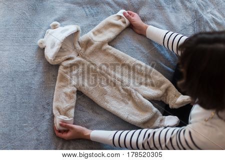 Pregnant woman dreaming and holding baby's clothes.