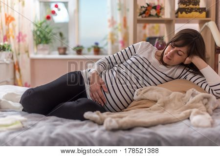 Pregnancy Woman sitting on sofa at home in bedroom