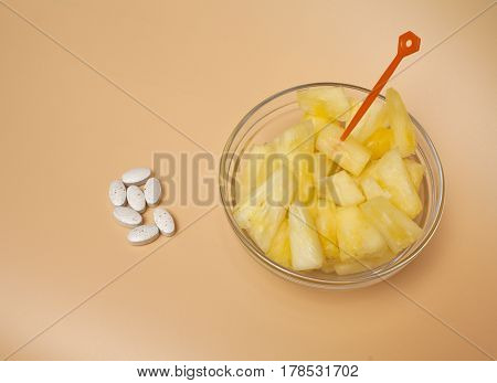 handful of pilule and cup filled with pineapple slices overhead view concept of healthy nutrition and prevention medicine