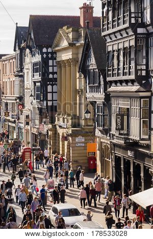 Chester England UK - March 25 2017: Shoppers and tourists making their way through Eastgate Street in the city centre with its mix of beautiful Tudor and neo-classical style buildings