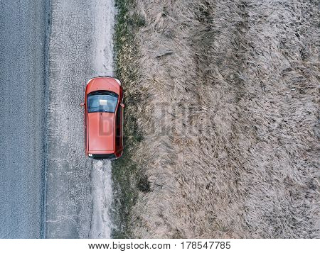 Red car on country road in spring time. Aerial view.