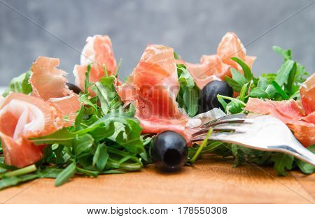 Chopping Board With Aragula And Raw Ham