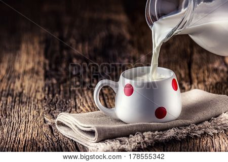 Milk. Cove or goat milk. Pouring milk into glass.