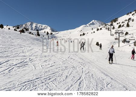 PYRENEES ANDORRA - FEBRUARY 9 2017: Unknown skiers on an alpine skiing in the Pyrenees Andorra. Sunny day the prepared route also in a shot the chair lift with people
