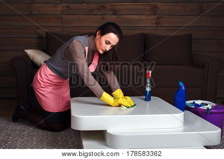 Woman in uniform and rubber gloves cleans table