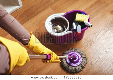 Female hands in rubber gloves wash floor with rag
