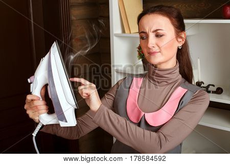Woman in uniform touches iron hot soleplate