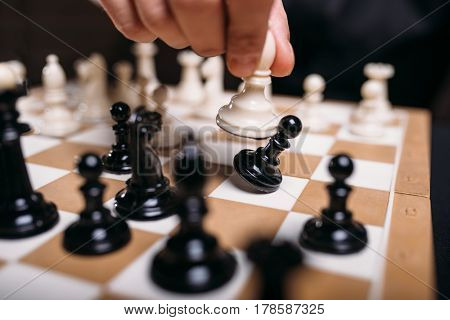 Male chess player hand holding white figure