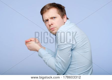 A Young Greedy Man Hides Something In His Hands And Looks Warily Forward.