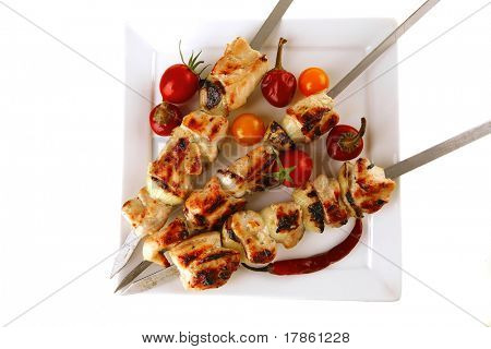 Chicken shish kebab på hvidt fad med grøntsager
