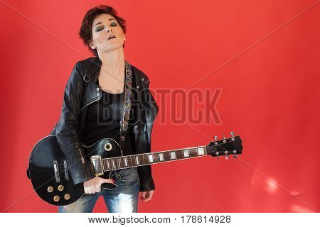 girl with short hair in leather jacket with a guitar