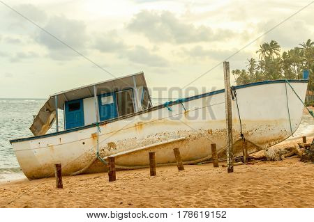 Old vintage blue and white boat on the shore of a tropical beach in south america