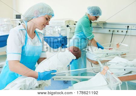 young female nurse holding a newborn baby in hospital