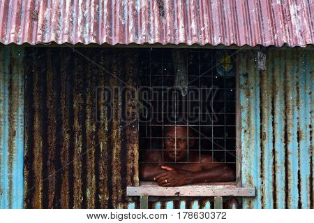 Indigenous Fijian man looks out of the window during a Tropical Cyclone storm.
