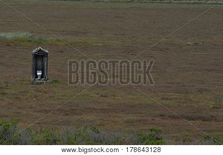 White toilet in outhouse in open field