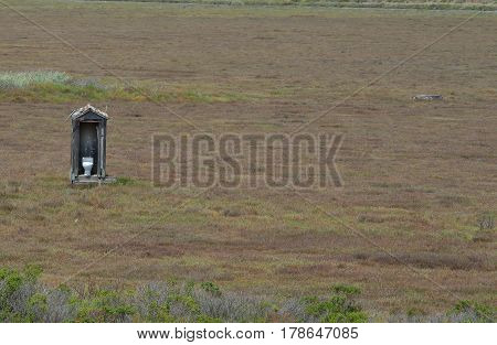 White toilet in outhouse out in open field