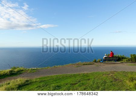 Mount Maunganui, New Zealand - March 27, 2017; Couple sitting near summit Mount Maunganui, taking a break and looking at the sea view.