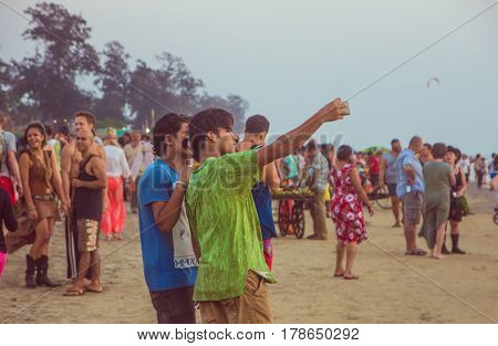ARAMBOL BEACH GOA INDIA - FEBRUARY 23 2017: Two indian man are taking photo on mobile on Arambol beach at sunset in Goa India on February 23 2017.