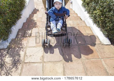 Mother carries a stroller down the stairs in garden without ramp for the disabled and baby prams