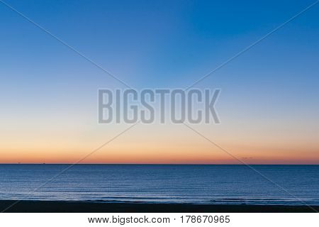 Deep blue sea red horizon and blue sky.