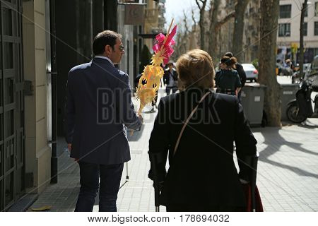 BARCELONA/ SPAIN - MARCH 29, 2015. A dapper man carrying a traditional decoration made of palm branches for Palm Sunday celebration at the Easter market. Barcelona, Spain